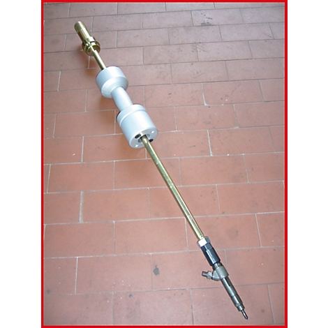 Ein Werkzeug auf einem braunen Fliesenboden. Das Werkzeug hat eine zylindrische Form mit verschiedenen Metallabschnitten.